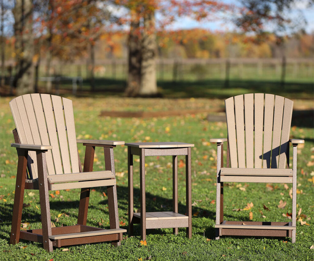 Two poly Adirondack chairs with side table on lawn in autumn.