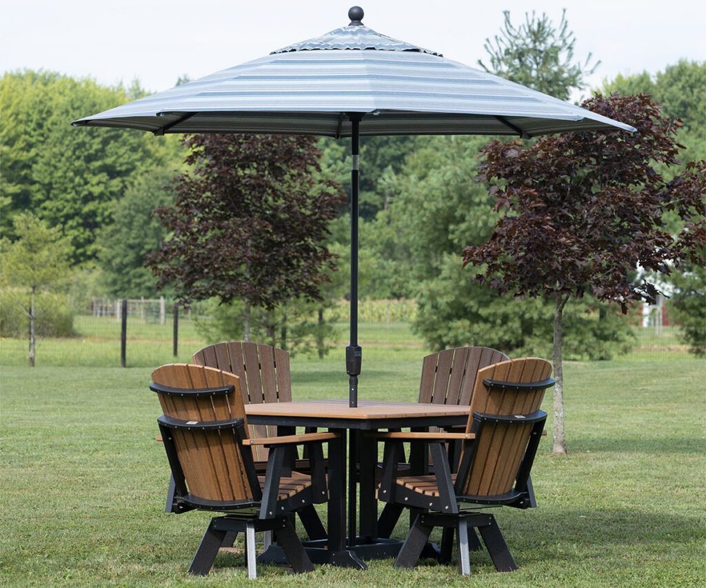 Poly patio table with umbrella and four chairs set on grassy backyard lawn.